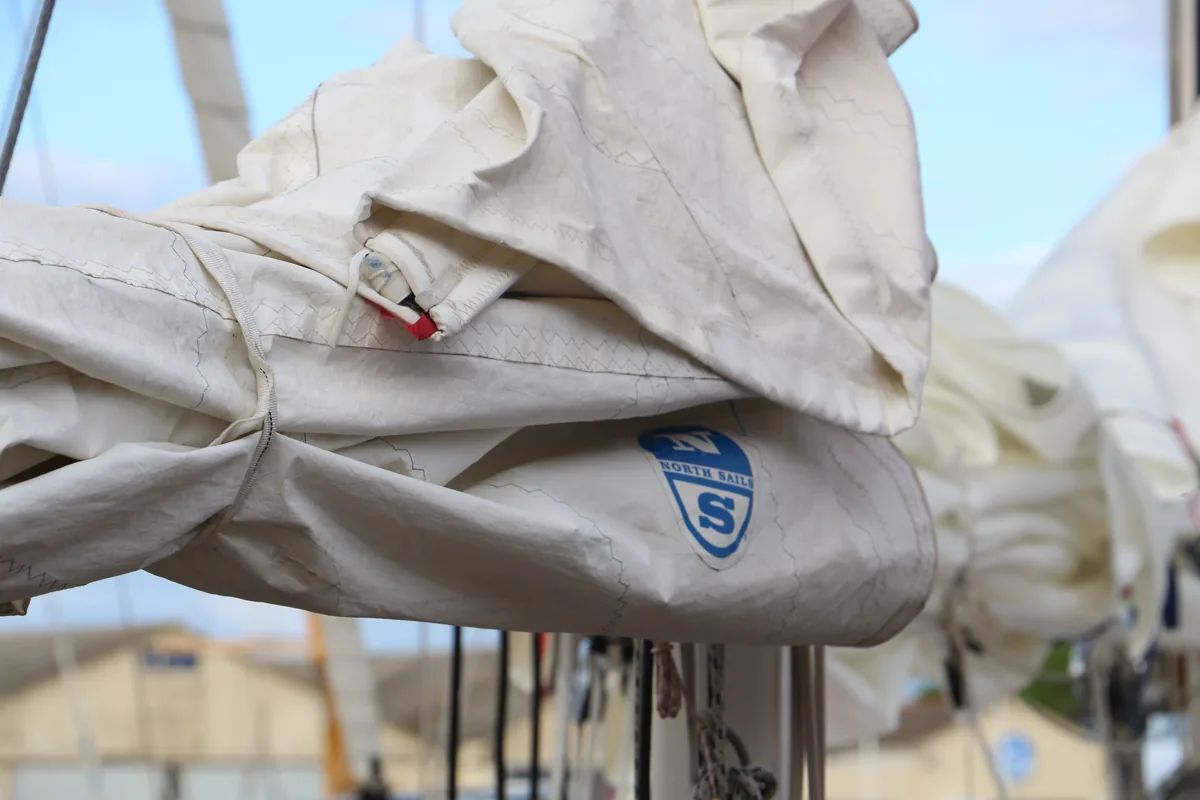 Mainsail furled on the boom of a classic yacht, the North Sails logo on the cloth.