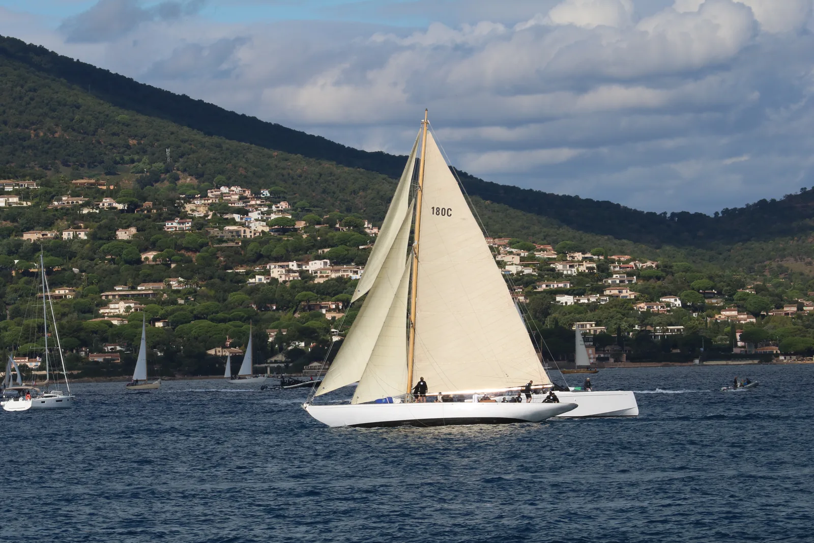 A classic yacht under sail in the gulf of Saint-Tropez, hills in the background.