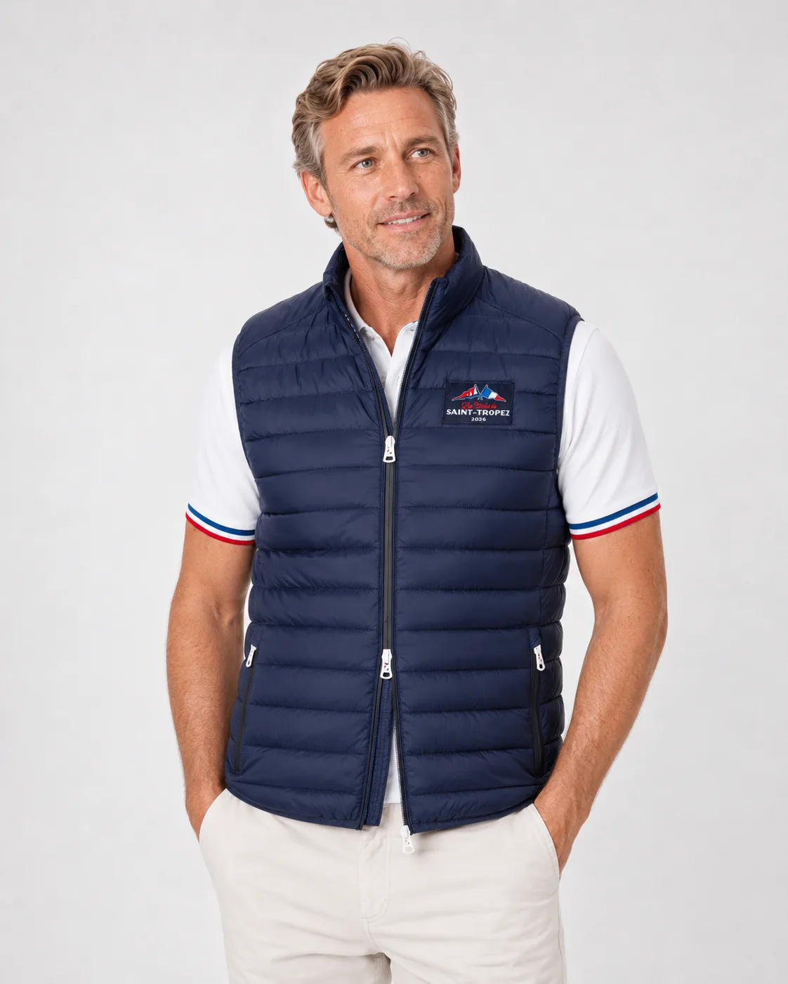 Doudoune Sans Manches 26 in navy worn over a white polo: stand collar, two-way zip, zipped side pockets and a woven edition label on the chest.