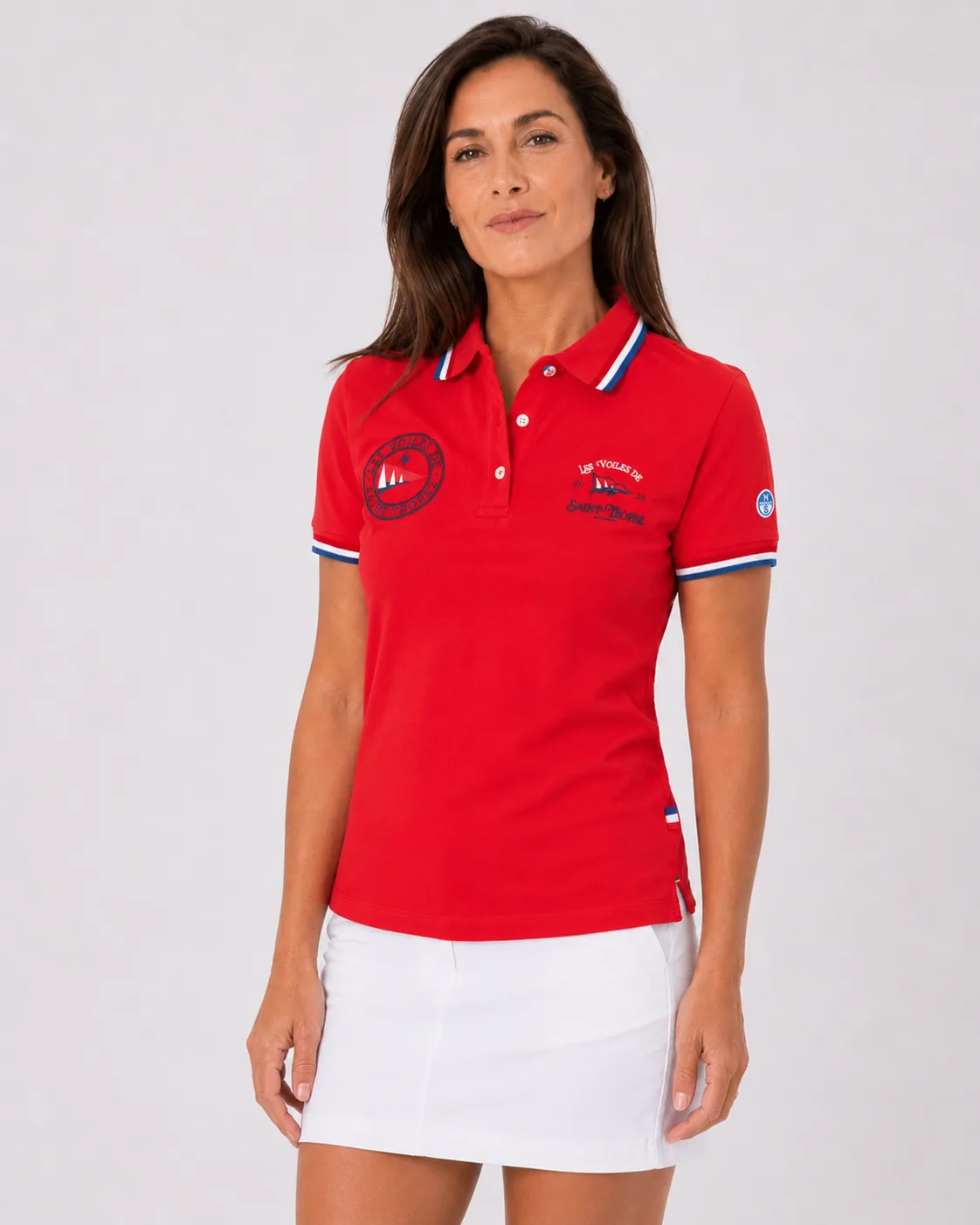 Polo Classique 26 in bougainvillea pink worn from the front: round badge on the left, Les Voiles de Saint-Tropez 2026 lettering on the right, tricolour tipping at the collar and cuffs, North Sails patch on the sleeve.