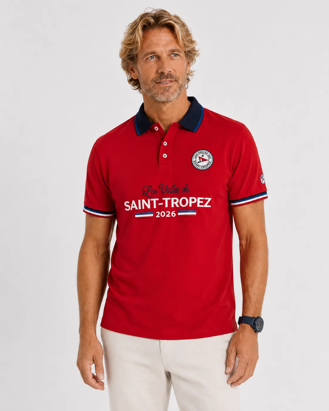 Polo Limited Edition 26 in bougainvillea pink seen from the front: navy collar, round badge, Les Voiles de Saint-Tropez 2026 embroidered large across the chest and tricolour tipping at the cuffs.