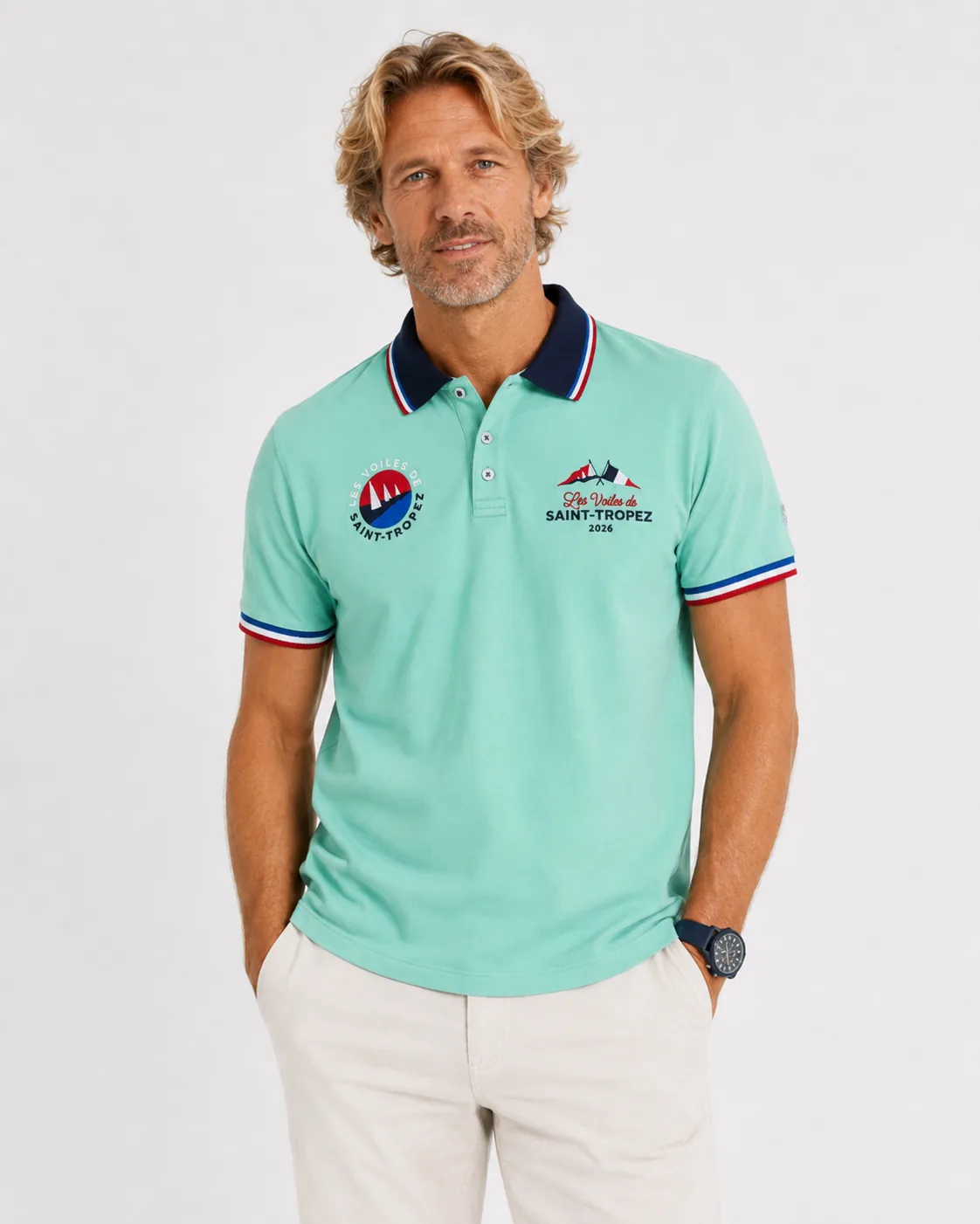 Polo Signature 26 in mint green seen from the front: navy collar with tricolour tipping, round badge on the left, Les Voiles de Saint-Tropez 2026 lettering on the right and a North Sails patch on the sleeve.