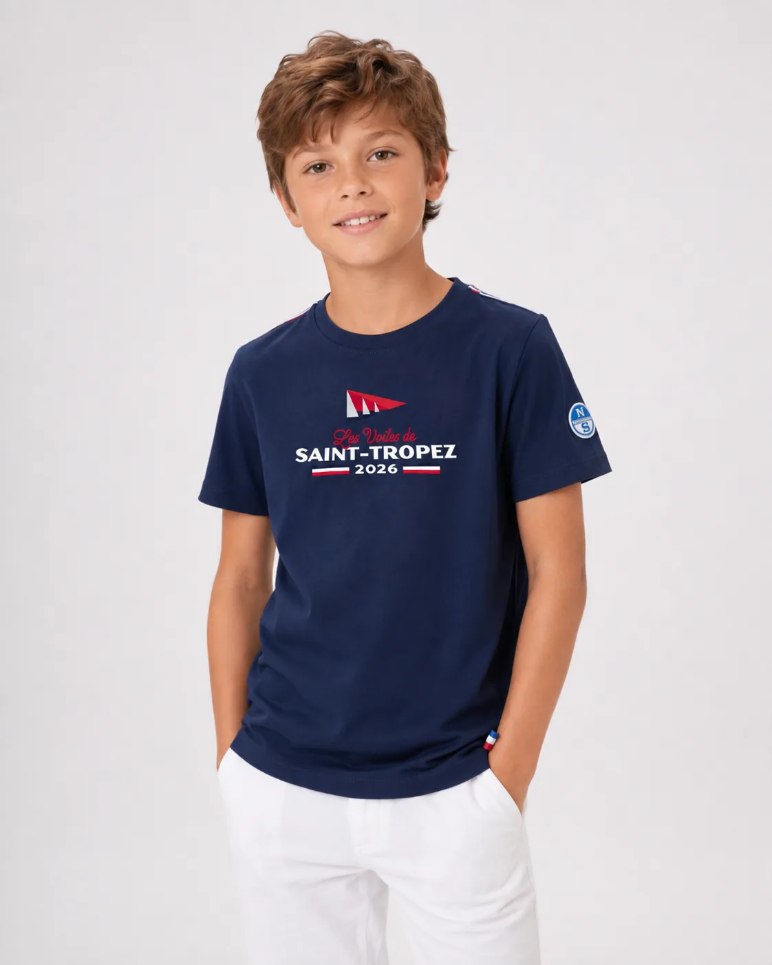T-Shirt Kids 26 in navy worn from the front by a child: Les Voiles de Saint-Tropez 2026 print on the chest and tricolour tape at the shoulder.